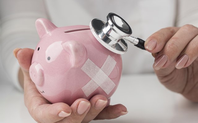 person-putting-stethoscope-piggy-bank
