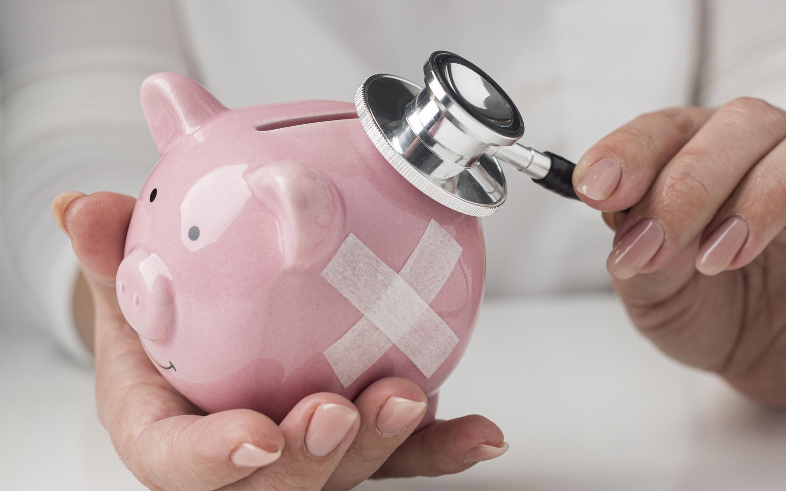 person-putting-stethoscope-piggy-bank